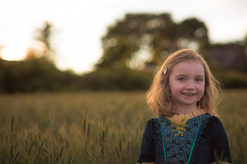 Little girl in wheat field at sunset