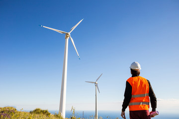 Ingegnere elettrico controlla l'impianto eolico con il gilet ad alta visibilità e casco bianco....
