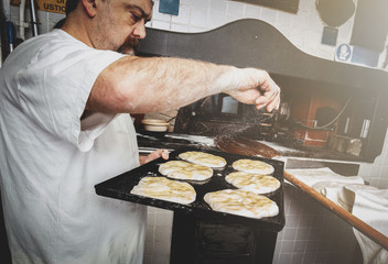 Production of baked bread with a wood oven in a bakery.