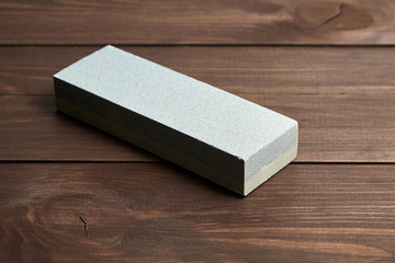 Rectangular double layer sharpening stone. Single grindstone or whetstone sharpener on wooden table background