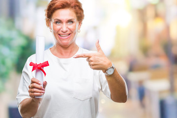 Senior caucasian woman holding degree certificate over isolated background very happy pointing with hand and finger