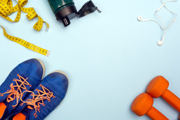 Sport concept with sport equipment composition. Sneakers, dumbbells, bottle of water on bright blue background