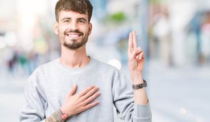 Young handsome man wearing sweatshirt over isolated background Swearing with hand on chest and...