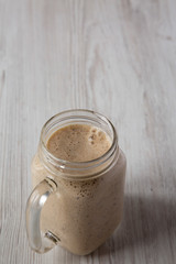 Mason jar mug filled with banana, kiwi, apple smoothie, low angle view. Copy space.