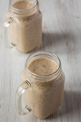 Mason jar mugs filled with banana, kiwi, apple smoothie, low angle view.