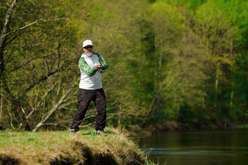 Naklejka premium Fisherman trying to do a perfect cast, throwing lure. Spining fishing, angling, catching fish. Hobby and vacation. Photo with shallow depth of field taken at wide open aperture.