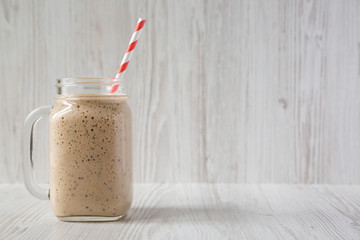 Homemade banana, kiwi, apple smoothie in a glass jar over white wooden background, side view. Copy space.