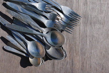 Old aluminium spoons and forks on a wooden surface. Old tableware