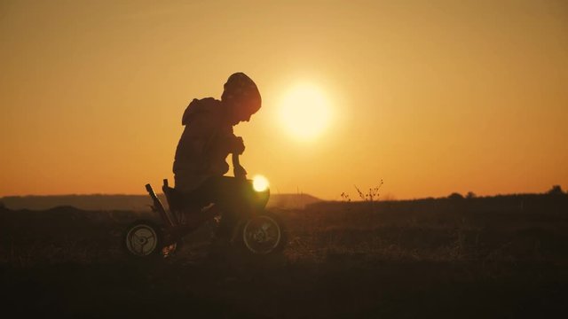 Silhouette of a girl on a bicycle on the background of sunset. Child having fun a bicycle in the sunset light.