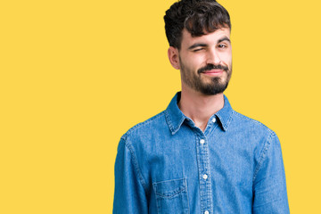 Fototapeta premium Young handsome man over isolated background winking looking at the camera with sexy expression, cheerful and happy face.