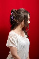 Portrait of young woman on red background. Attractive lady with long wavy brown hair in white blouse