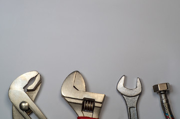 Necessary set of tools for plumbers on a gray background.