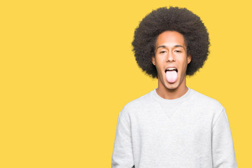 Obraz na płótnie Canvas Young african american man with afro hair wearing sporty sweatshirt sticking tongue out happy with funny expression. Emotion concept.
