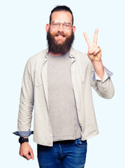 Naklejka premium Young blond man wearing glasses showing and pointing up with fingers number two while smiling confident and happy.