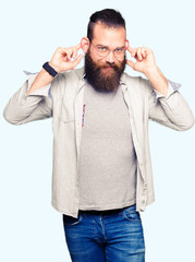 Fototapeta premium Young blond man wearing glasses Smiling pulling ears with fingers, funny gesture. Audition problem