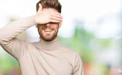 Young handsome business man wearing glasses smiling and laughing with hand on face covering eyes for surprise. Blind concept.