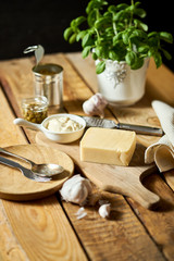 Cheese and grater fresh basil with can and sauce on wooden kitchen table