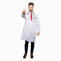 Young handsome doctor man wearing medical coat Pointing with finger up and angry expression