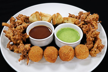 assorted indian snack pakora plater with paneer balls, onion crisps and panjabi samosa