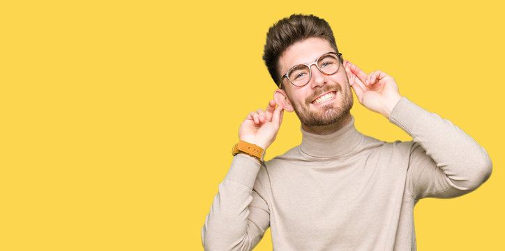 Young handsome business man wearing glasses Smiling pulling ears with fingers, funny gesture. Audition problem