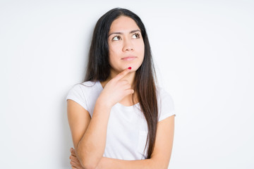 Fototapeta premium Beautiful brunette woman over isolated background with hand on chin thinking about question, pensive expression. Smiling with thoughtful face. Doubt concept.