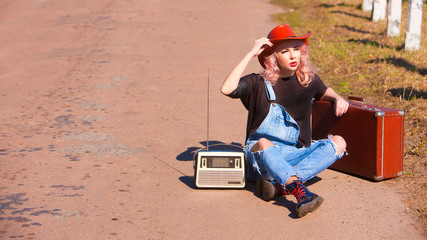 Beautiful traveling woman with retro suitcase on the road	