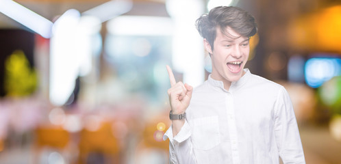 Young handsome business man over isolated background with a big smile on face, pointing with hand and finger to the side looking at the camera.