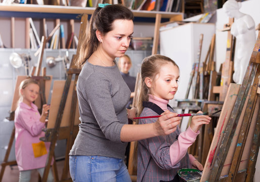 Teacher assisting student during painting class at studio
