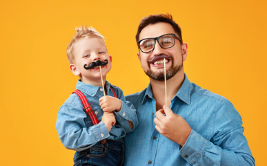 happy father's day! funny dad and son with mustache fooling around on yellow background.