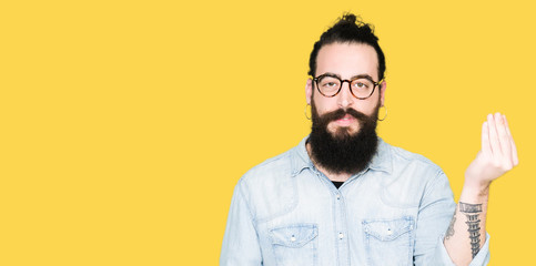 Young hipster man with long hair and beard wearing glasses Doing Italian gesture with hand and fingers confident expression