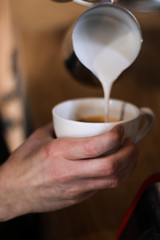 barista man preparing coffee (cappuccino), pouring milk