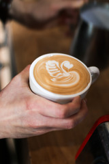 Fototapeta na wymiar barista man preparing coffee (cappuccino with a swan latte art), pouring milk