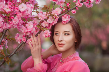 Beautiful woman in the garden of sakura. Retro clothes, pink blouse.