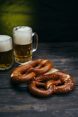 pretzels and beer in the mug on dark wooden background