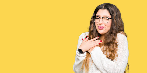 Young beautiful woman wearing glasses smiling with hands on chest with closed eyes and grateful gesture on face. Health concept.