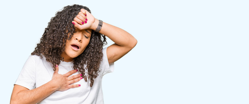 Young beautiful woman with curly hair wearing white t-shirt Touching forehead for illness and fever, flu and cold, virus sick