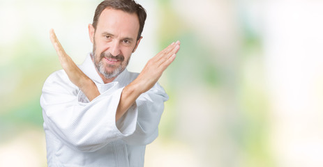 Handsome middle age senior man wearing kimono uniform over isolated background Rejection expression crossing arms doing negative sign, angry face