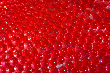 Water red gel balls with bokeh. Polymer gel. Silica gel. Balls of red hydro-gel. Crystal liquid ball with reflection. Red balls texture background