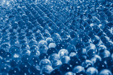 Water blue gel balls with bokeh. Polymer gel. Silica gel. Balls of blue hydro-gel. Crystal liquid ball with reflection. Blue balls texture background