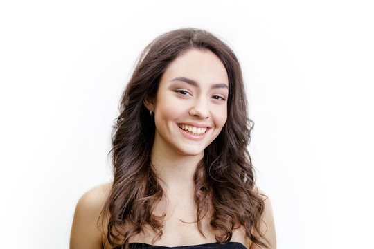 Closeup Studio Portrait Of Beautiful Smiling Young Woman. Girl Has Long Brown Hair With Curls. She Has Black Strapless Dress. Isolated On White Background.