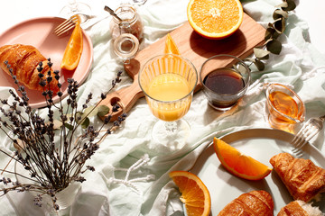 Croissants and oranges on a blue tablecloth