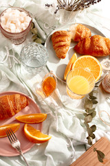Croissants and oranges on a blue tablecloth