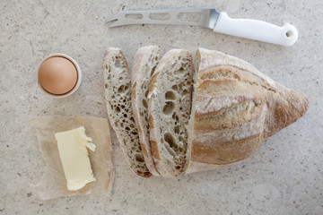 Top view of simple breakfast, sliced homemade bread, boiled egg and butter on the table 