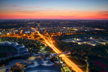 Modern European cityscape aerial view in blue hour with office buildings, high tower blocks, parks, overpass and highway junction in outskirts lit by car lights, Moosach Milbertshofen Munchen Germany