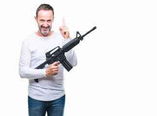 Fototapeta na wymiar Middle age senior hoary criminal man holding gun weapon over isolated background surprised with an idea or question pointing finger with happy face, number one