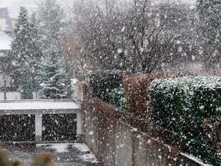 Snow falling over interior courtyard of a real estate property with two garages entrance 