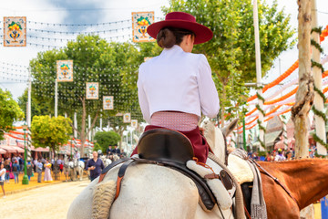 Fototapeta premium Beautiful Women riding horses and celebrating Seville's April Fair, Seville Fair (Feria de Sevilla). The Seville April Fair on May, 5, 2019 in Seville, Spain
