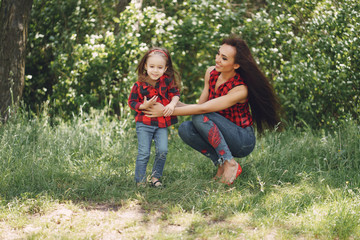 Fototapeta premium Young and very beautiful slim mum with long hair walking in a sunny summer park with her little beauties daughter