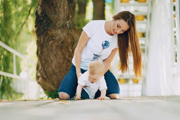 a beautiful young long-haired mom sitting in the park with her beautiful little son