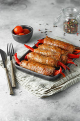 Meat rolls stuffed with sweet red paprika in heat-resistant black dish on a grey background